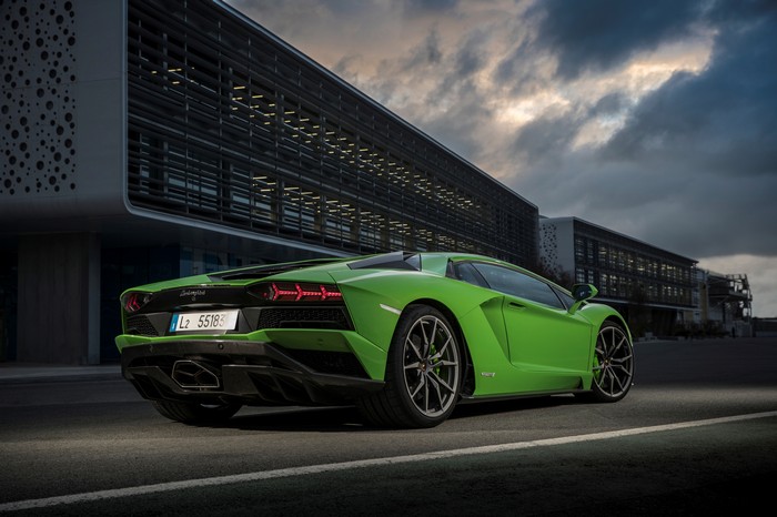 Green Lamborghini Aventador S parked near a modern building