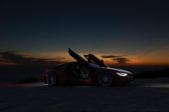 Red BMW i8 with butterfly doors at sunset