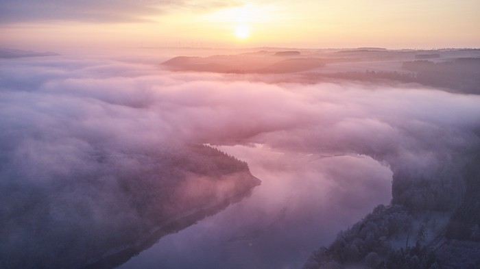 Sunrise over a misty lake and forest