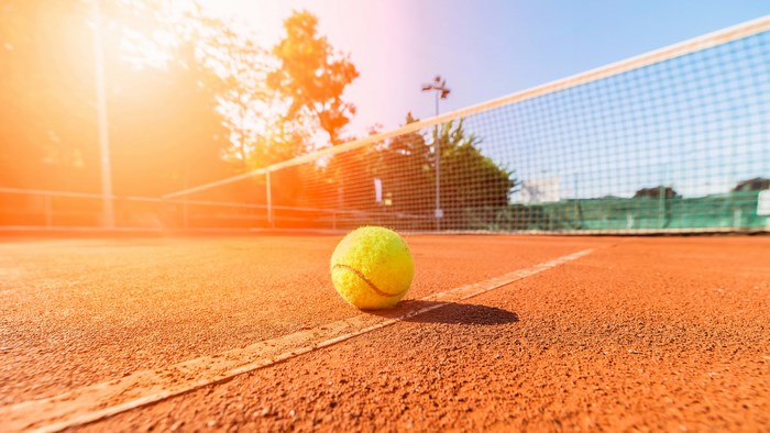 Tennis Ball on Clay Court at Sunset
