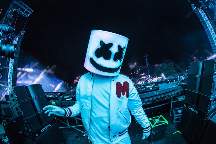 Marshmello performs on a stage with lights and speakers