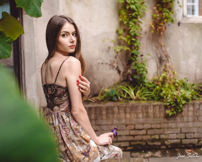 Woman in patterned dress holding a flower outdoors