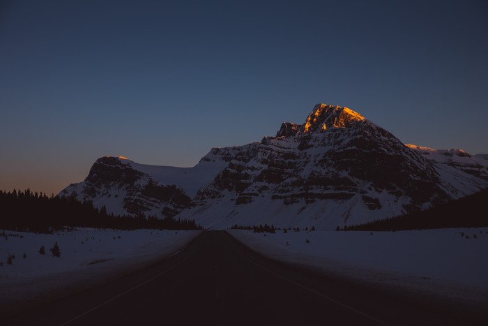 Snowy mountains at sunset with a road
