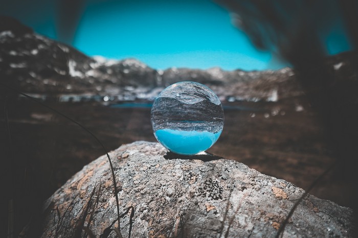Crystal ball reflecting mountains and blue water