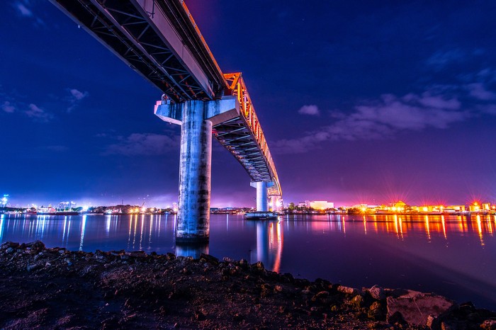 Colorful bridge over water at night with city lights