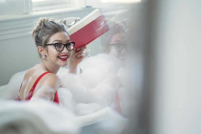 Gigi Hadid in a bubble bath reading a book