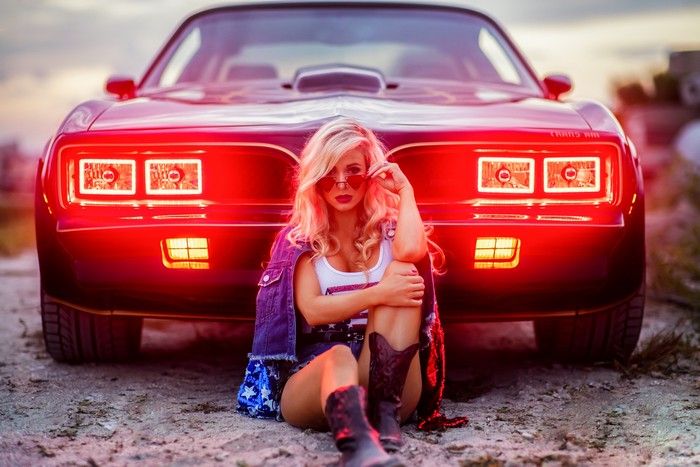 Woman in denim jacket and cowboy boots with Trans Am