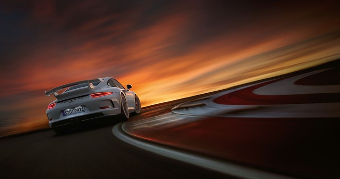 Porsche 911 GT3 R on a race track at sunset