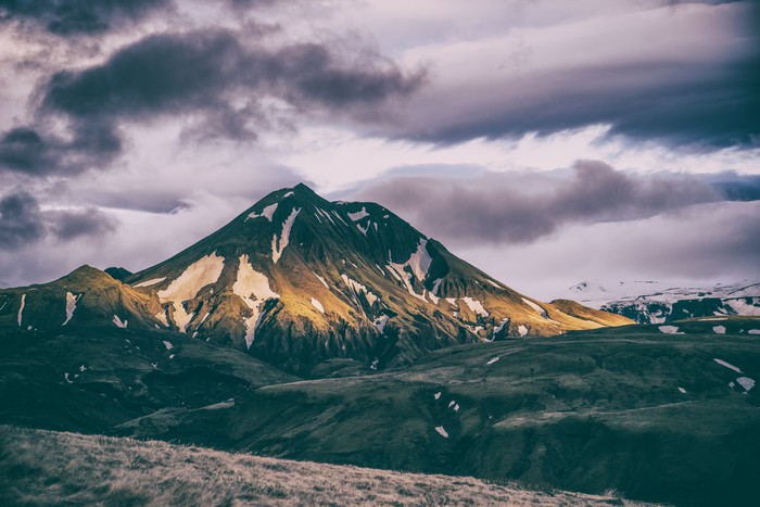 Mountains landscape with snow patches under cloudy sky