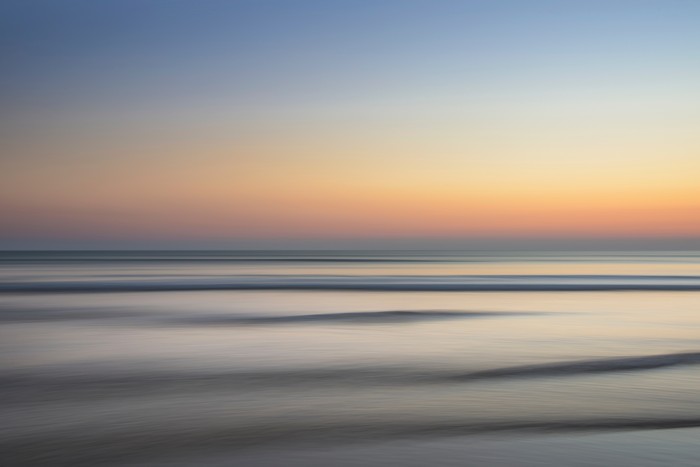 Minimalist sunset over the ocean with waves