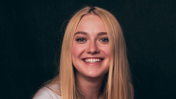 Dakota Fanning smiling against a dark background