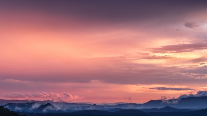 Pink and purple sunset over misty mountains