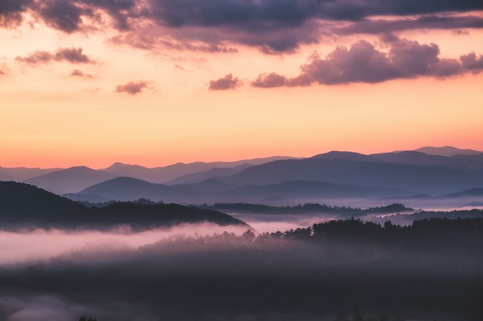 Mountain range at sunrise with fog