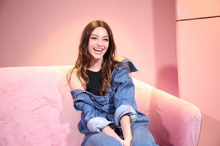 Celine Farach smiling on a pink couch
