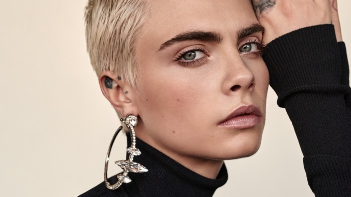 Cara Delevingne wearing a black turtleneck and large earrings