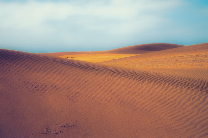 Desert sand dunes under a cloudy sky