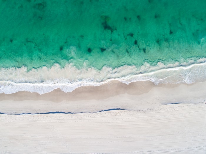 Aerial view of a tropical beach with turquoise ocean waves