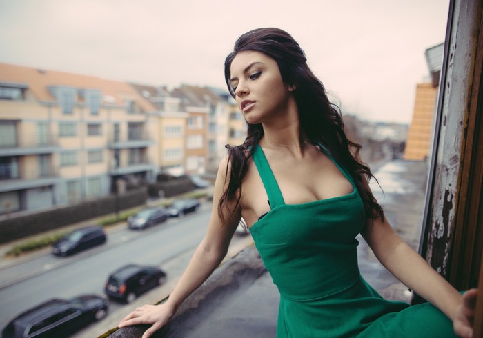 Woman in green dress on balcony overlooking city