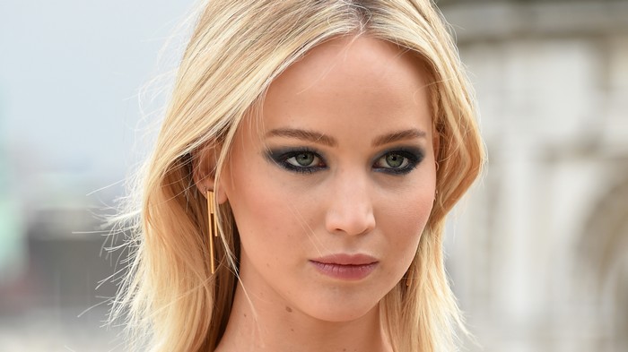 Jennifer Lawrence with dark eye makeup and gold earrings