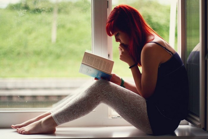 Woman reading a book by the window