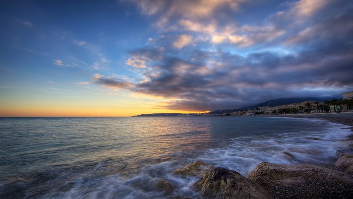 Coastal city skyline at sunset with ocean waves