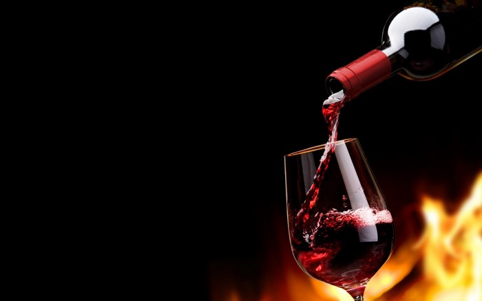 Red wine being poured from bottle into glass with flames