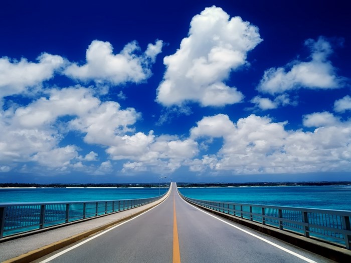 Bridge over turquoise water under blue sky with clouds