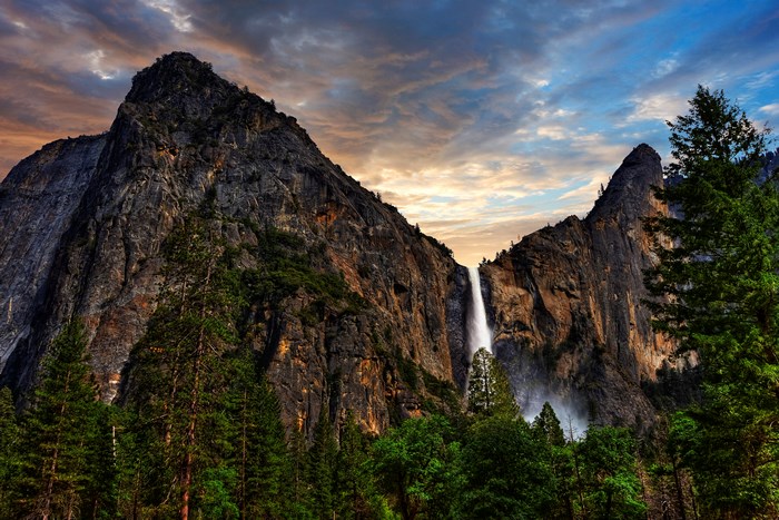Waterfall cascading down rocky cliffs with pine trees