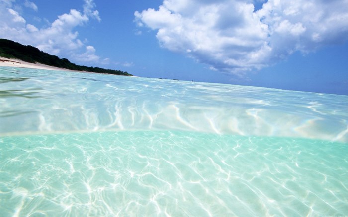 Crystal clear ocean water with sandy beach and blue sky