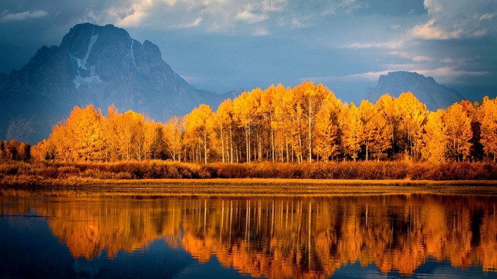 Autumn trees reflecting in a lake with mountains