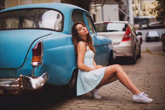 Woman leaning on a vintage blue car