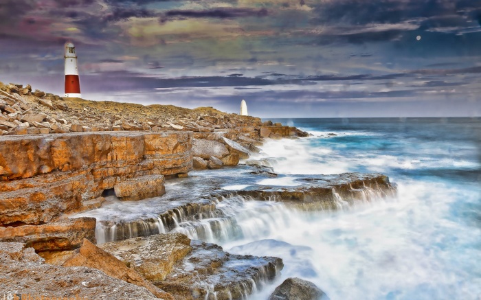 Portland Bill Lighthouse on rocky coast with waves