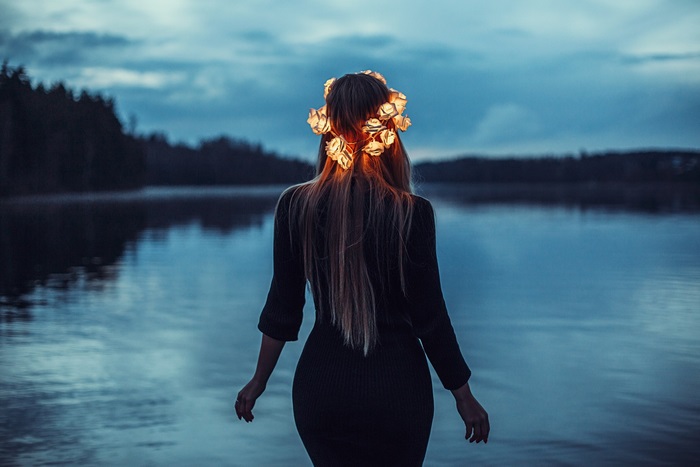 Girl with flower crown by lake at dusk