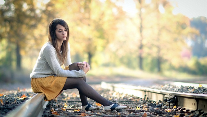 Woman Sitting Thoughtfully on Railroad Track in 4K