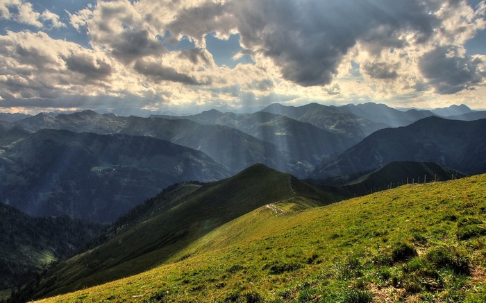 Sunbeams through clouds over mountain range