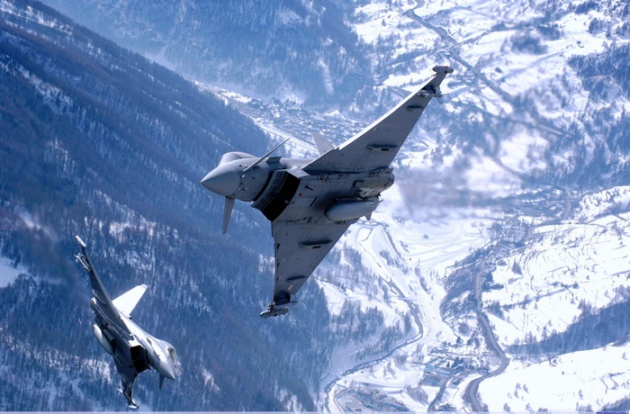 Eurofighter Typhoons flying over a snowy mountain village