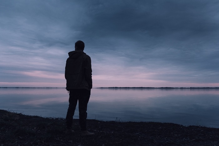 Man standing by a lake at dusk