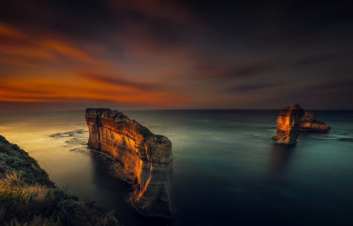 Rock formations in the ocean at sunset