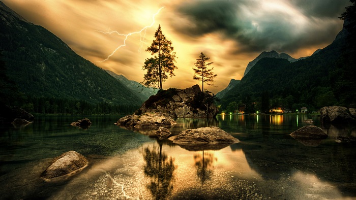 Lightning over a lake with mountains