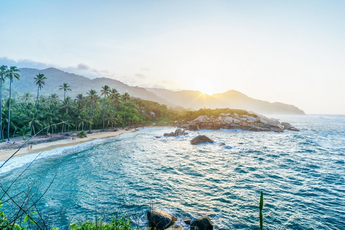 Beach with palm trees and mountains at sunset