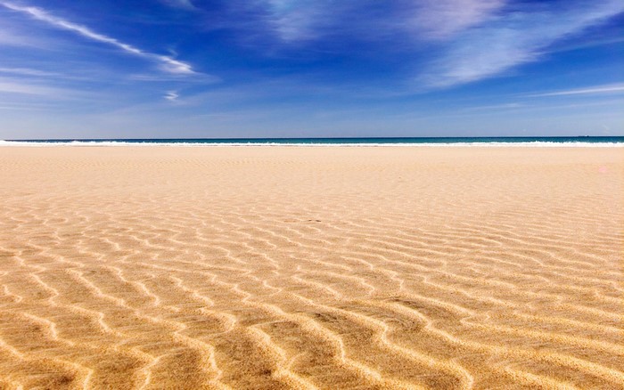 Beach with sand ripples and blue sky