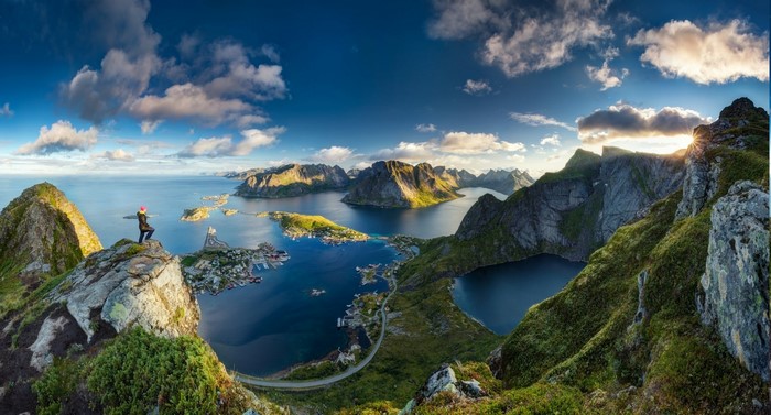 Person on mountain overlooking Lofoten Islands, Norway at sunrise