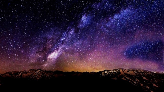 Starry Night Sky Over Snow-Capped Mountains