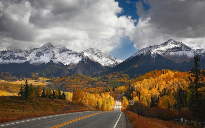 Snowy mountains and autumn forest along a winding road