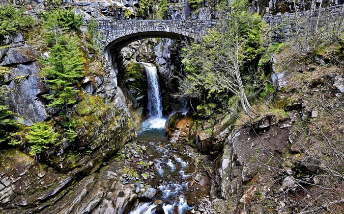 Stone bridge over a waterfall and stream in a rocky gorge