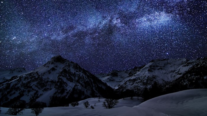 Snowy mountains under a starry night sky