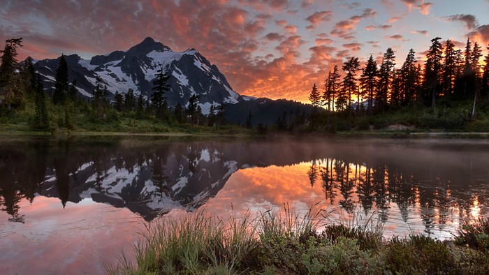 Mountain lake reflection at sunrise with colorful clouds