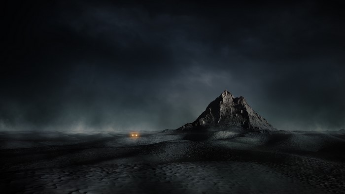 Dark desert landscape with mountain and car headlights