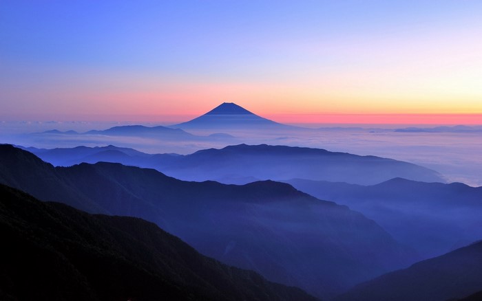 Mount Fuji at sunrise over misty mountains in Japan