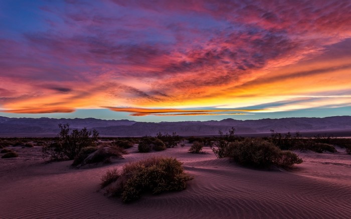 Desert sunset over sand dunes and mountains